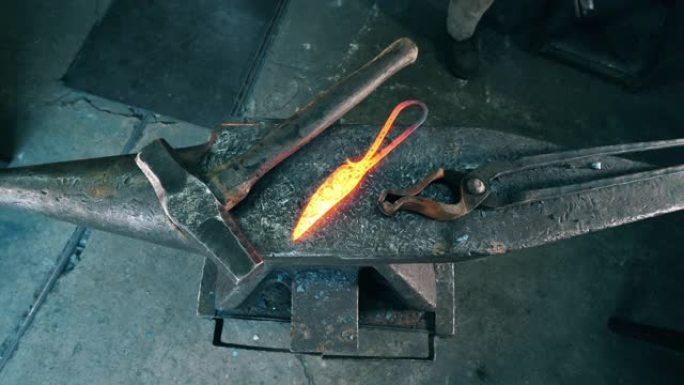 专业铁匠将热刀放在铁砧上。
