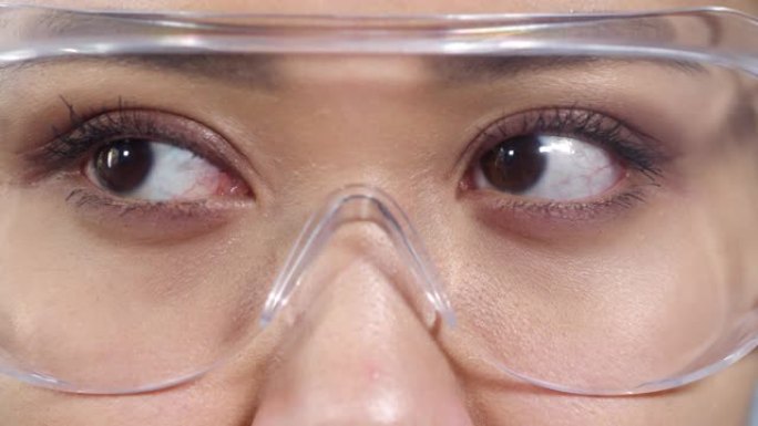 穿着透明护目镜的亚洲女人的眼睛看着东西