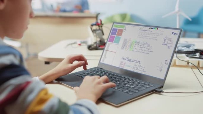 小学计算机科学教室: 使用笔记本电脑为机器人课程设计和编程的孩子的肩膀视图