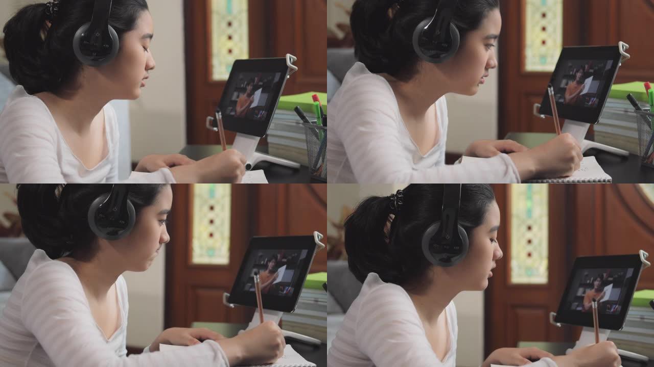 4k分辨率迷人的亚洲少女戴着耳机，在冠状病毒或covid 19锁定情况下，与老师一起在平板电脑屏幕上