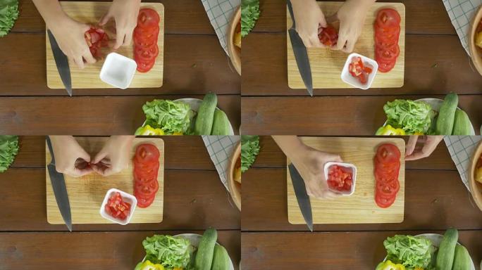 女酋长在厨房的切菜板上制作沙拉健康食品和切碎番茄的俯视图。