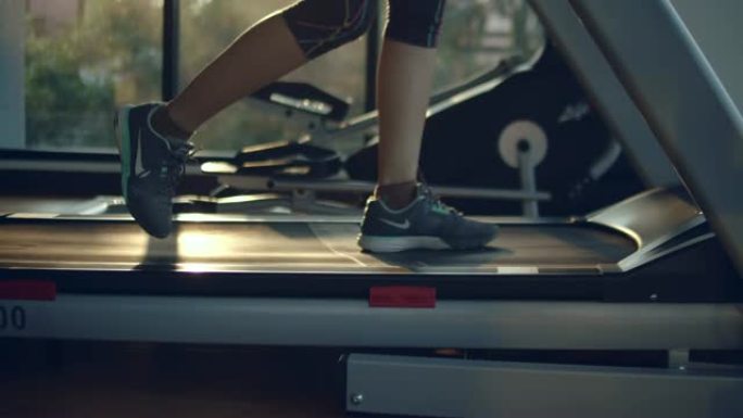 年轻的亚洲妇女在健身房的跑步机上跑步