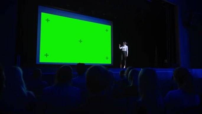 在舞台上: 有远见的演讲者在她的电影院后面用绿屏，模型，色键演示新产品。女首席执行官在业务现场活动或