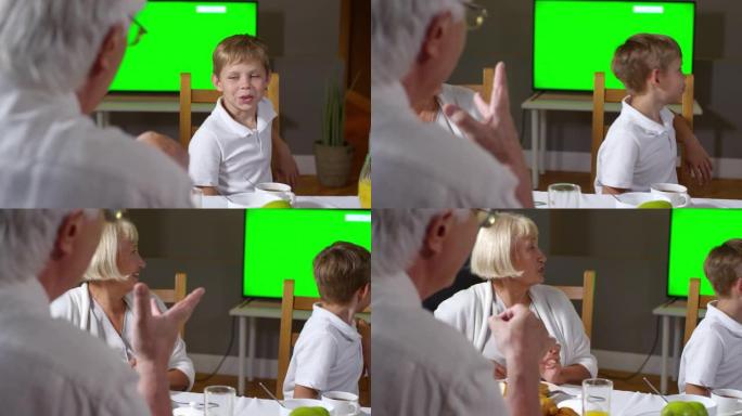 小男孩和祖父母一起吃早餐看电视