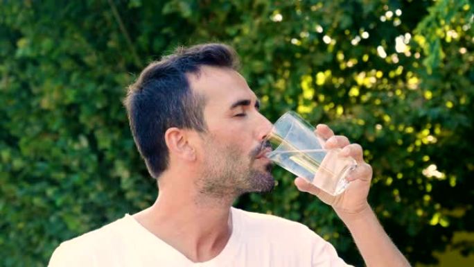 一个沉浸在大自然中的微笑的人喝一杯水，以净化自己的身体，缓解自己并改善利尿。