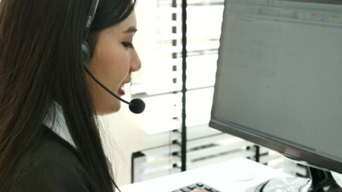 在呼叫中心工作的年轻亚洲女性使用耳机与客户交谈