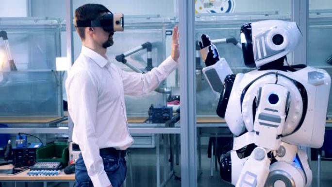 一位戴着VR眼镜的人给机器人击掌。