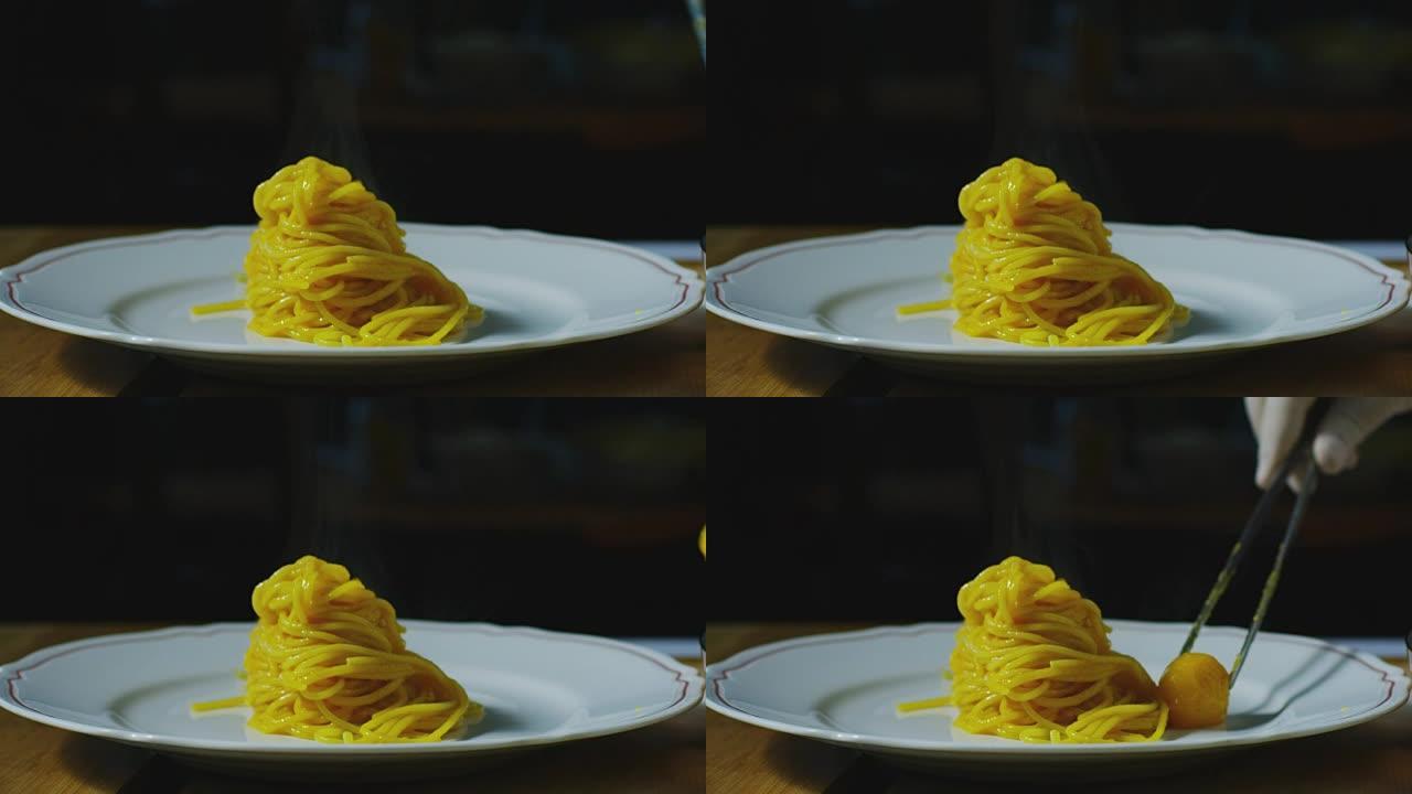 中年厨师用白色盘子上的黄色西红柿装饰面食的超级慢动作宏观 (特写)
