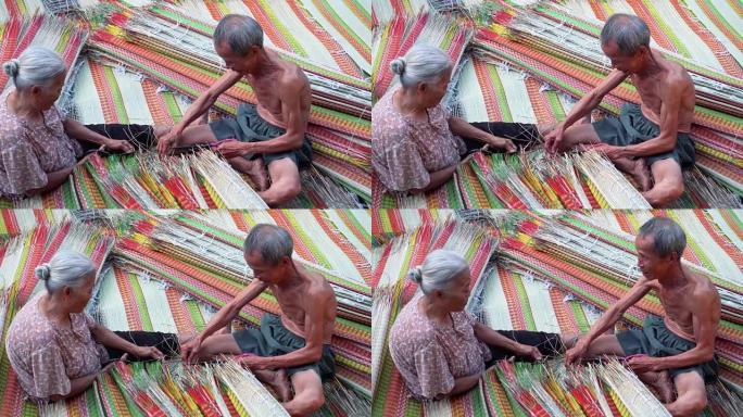 4k镜头场景两位越南老工匠在越南东塔丁延的老传统村庄制作和修剪传统越南垫子的俯视图，传统艺术家概念