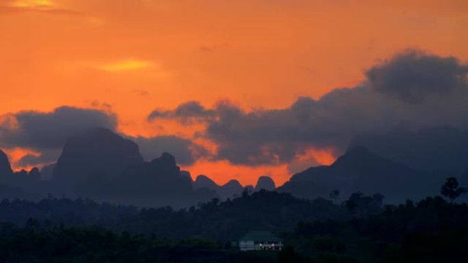 热带的橙色日落天空。黄昏时山脉的轮廓。泰国考索克国家公园。平移镜头