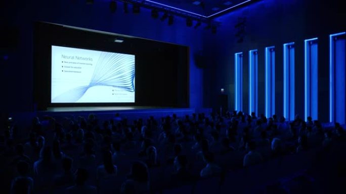 电影院里的技术人员在大屏幕上观看高科技新产品神经网络机器学习软件演示。科技产业商务会议礼堂大厅人满事