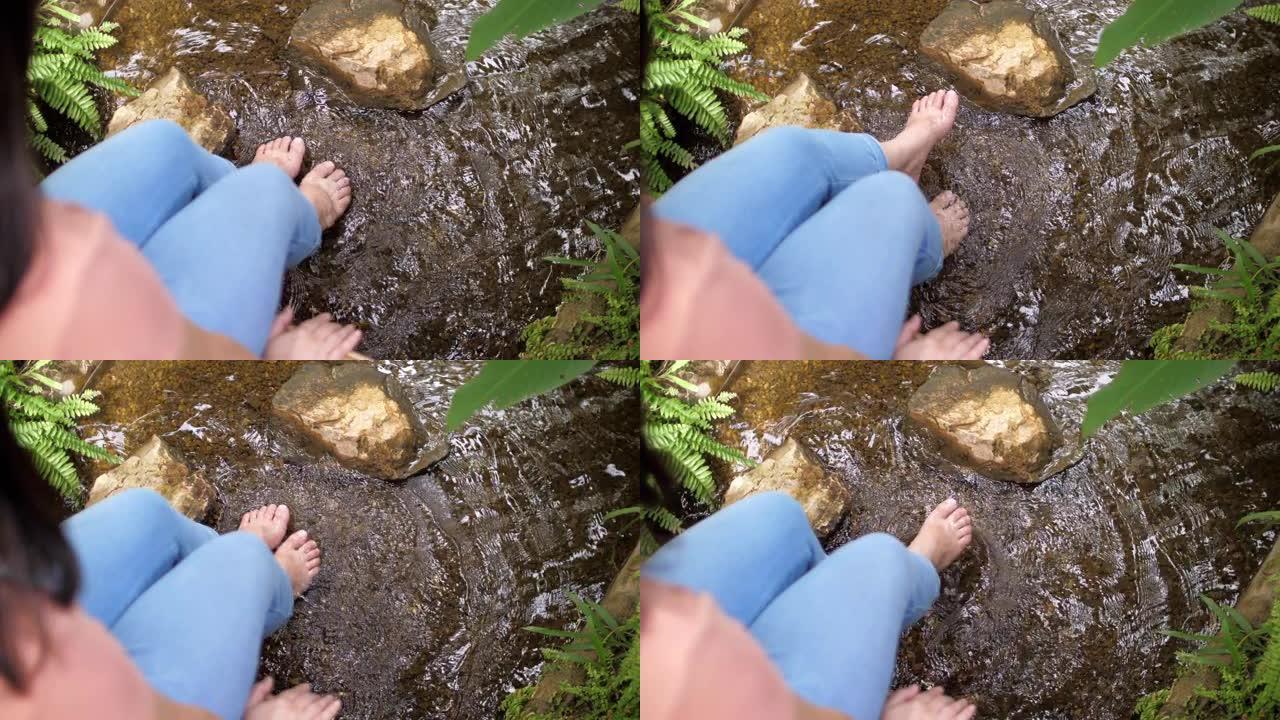 女人的脚浸泡在溪流瀑布中放松