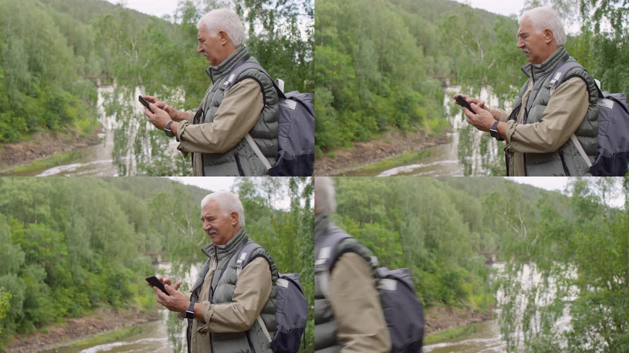 老人用手机徒步旅行