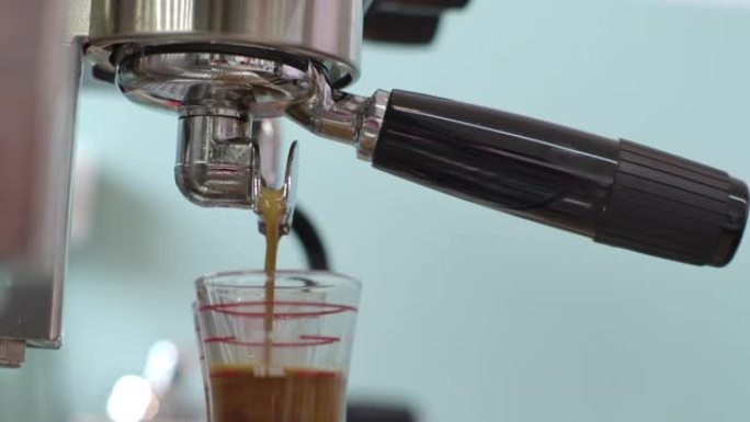 慢动作浓缩咖啡机将咖啡倒入玻璃杯中，制成浓缩咖啡和卡布奇诺咖啡