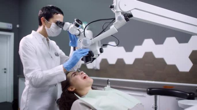 女性医学专家使用牙科显微镜和检查患者