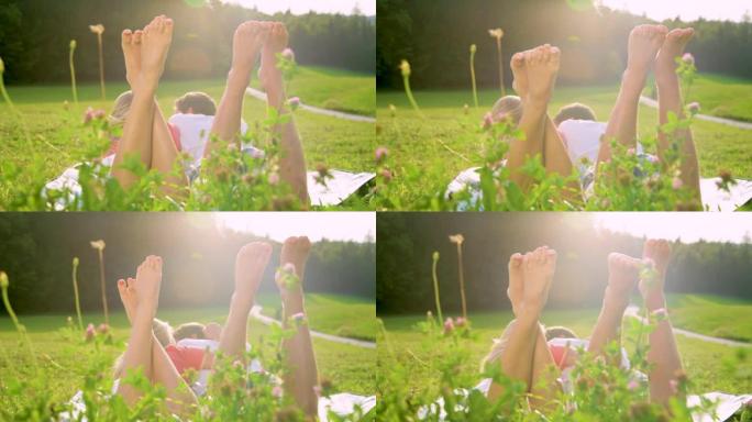 慢动作: 男人和女人躺在草地上嬉戏地踢他们的赤脚