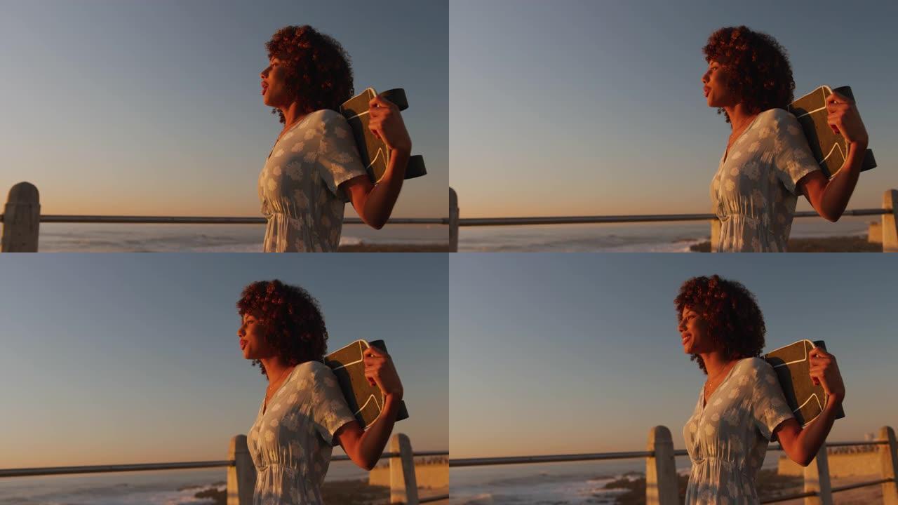 女人走路手拿滑板黄昏海边黑人女性旅游