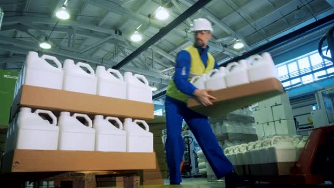 工业工人正在用塑料罐堆叠纸箱托盘