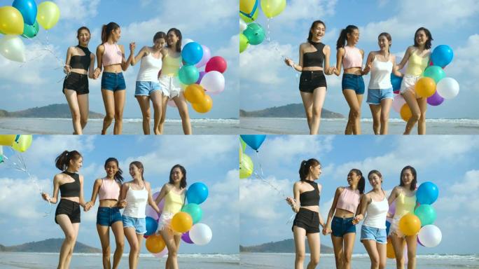 时髦的朋友带着快乐的心情抱着五颜六色的气球走在海滩上。有派对庆祝概念的人。4k分辨率。慢动作镜头。