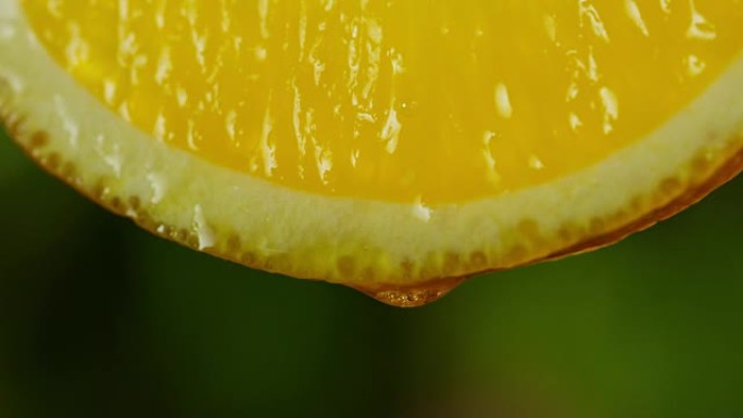 关闭或微距一片柠檬，一滴水以慢动作落下。水果散发出新鲜感和果汁馅。