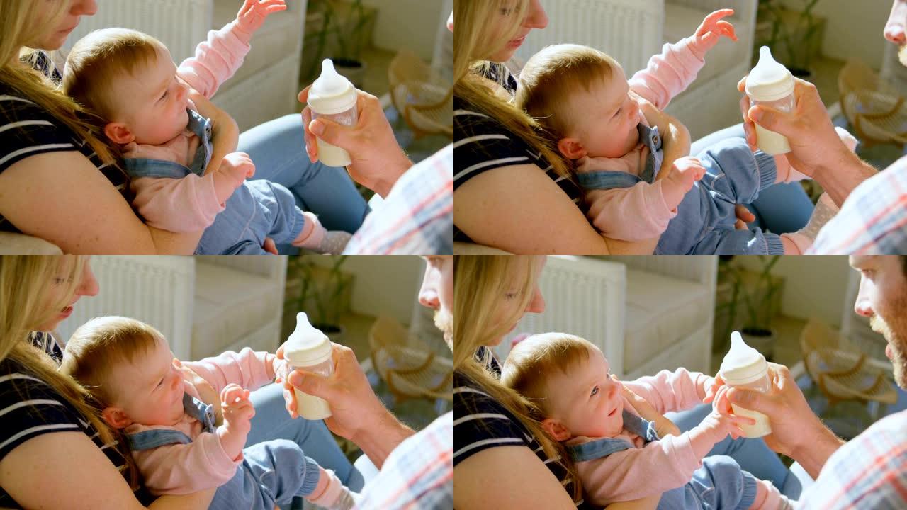 中年白人父母在一个舒适的家庭4k从奶瓶里给婴儿喂奶