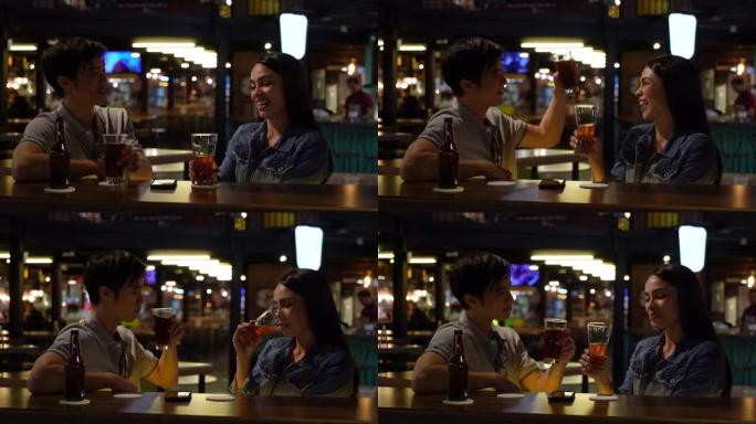 快乐的多元化夫妇在酒吧玩得开心，喝啤酒，举杯大笑