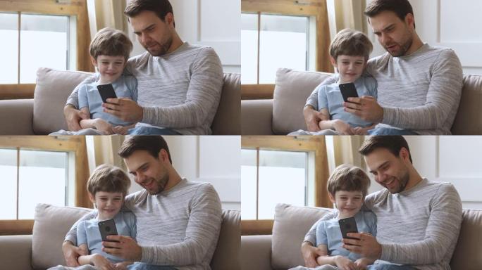 爸爸教孩子儿子在沙发上用手机玩得开心
