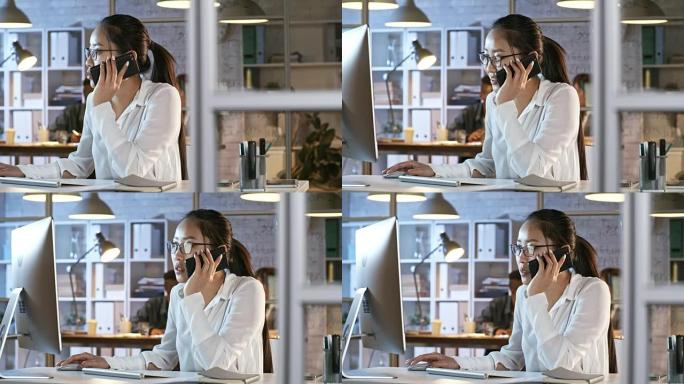 亚洲女经理在电话上聊天并在计算机上工作