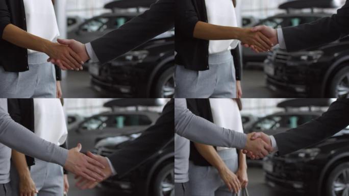 推销员在汽车陈列室与男人和女人握手