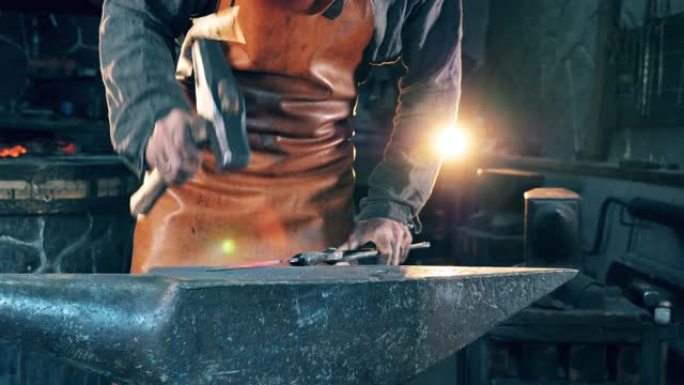 一个铁匠用锤子在锻炉上塑造刀。