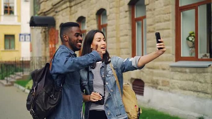兴奋的游客男人和女人正在用智能手机手持设备进行在线视频通话，并交谈表示竖起大拇指，表达积极的情绪。
