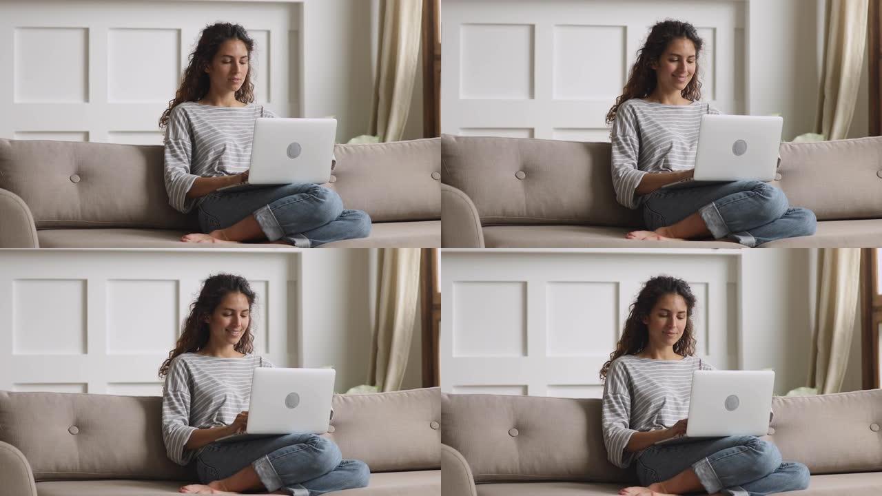 愉快的年轻卷发女人在家使用电脑。