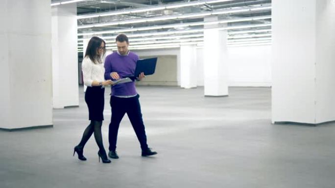 女人和男人在商业区散步时用笔记本电脑工作，专业工程师。