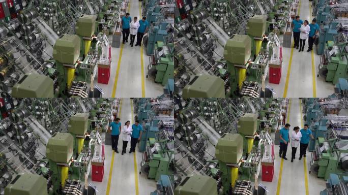 主管指导生产线上的体力劳动者拿着平板电脑，指着橡胶带工厂的机器