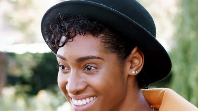 戴着洪堡帽子的卷曲流苏的年轻黑人妇女的头部镜头大笑，特写