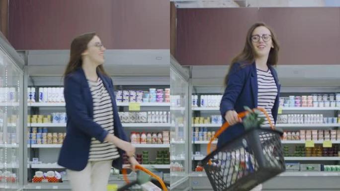 在超市: 快乐的年轻女孩拿着购物篮在商店的冷冻商品和乳制品区跳舞。垂直屏幕方向视频9:16