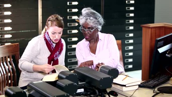 图书馆中的妇女与缩微胶片阅读器进行研究