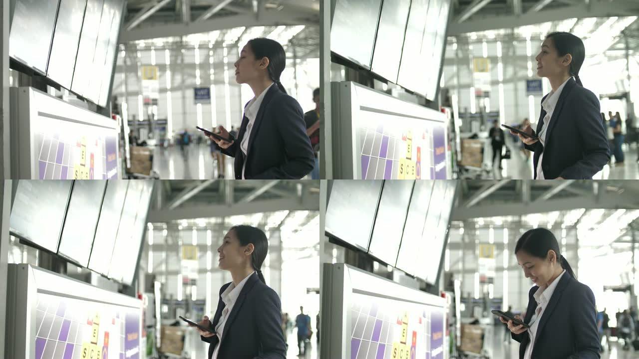 女商人用智能手机看着机场出发板