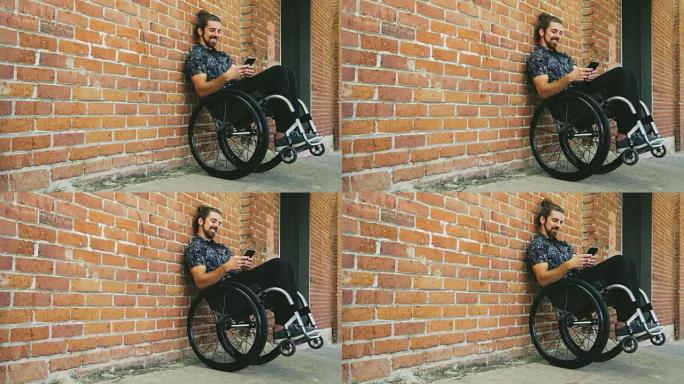 年轻快乐的残疾人男子坐在轮椅上靠着砖墙发短信
