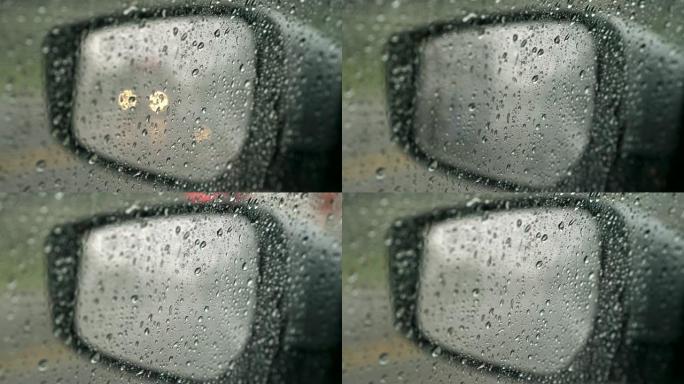 下雨时车窗和镜子上的雨滴。镜子上的散焦交通灯