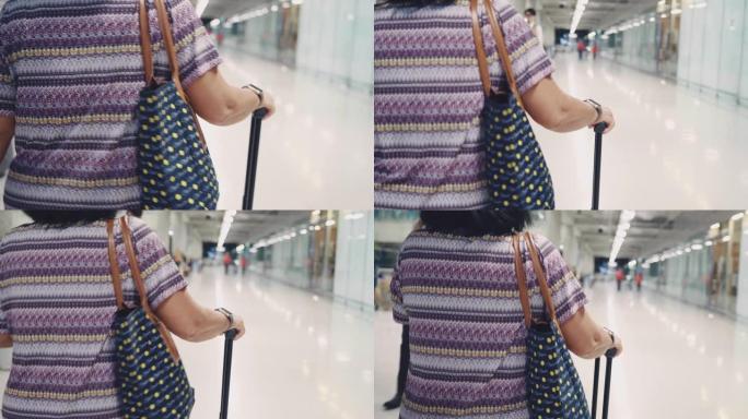 亚洲高级妇女在机场散步和拉行李箱
