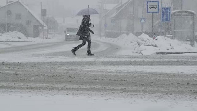慢动作: 在暴风雪中，无法识别的女人穿过白雪皑皑的街道。
