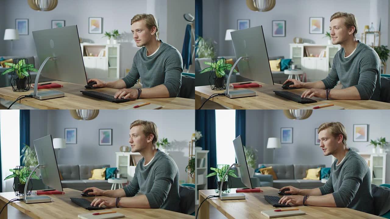 那个英俊的男人坐在办公桌前在个人电脑上工作的肖像。背景时尚舒适的客厅。年轻的自由职业者在家工作。