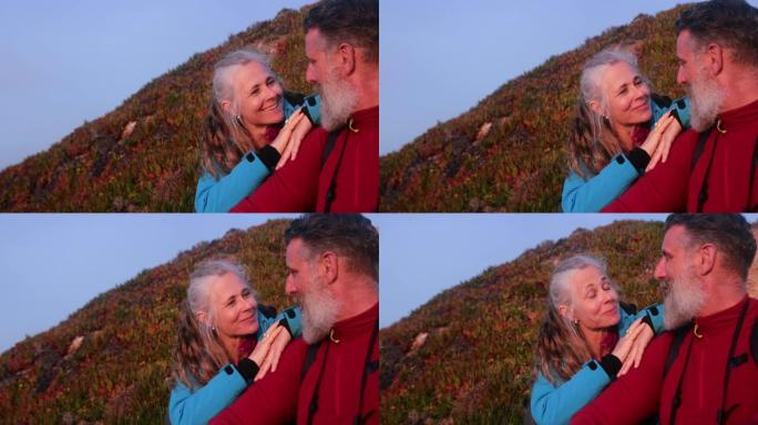 高年级高加索夫妇坐在悬崖上看着日落