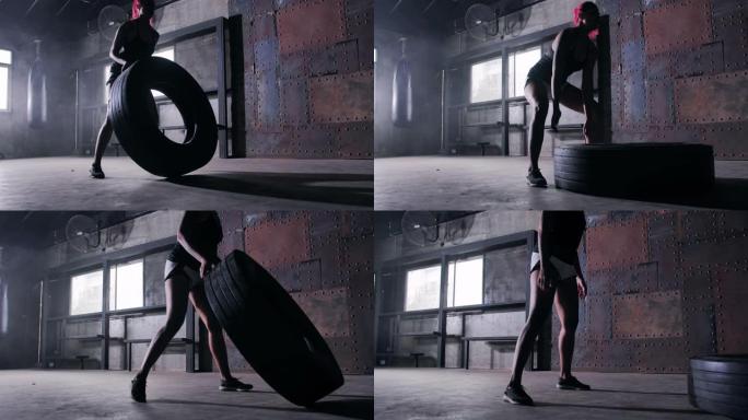 强壮的女人在推轮胎。女人用大轮胎锻炼。在健身房刻苦训练。武术