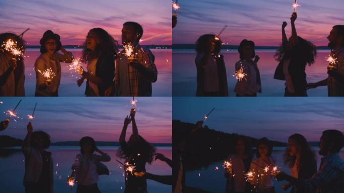 笑着的朋友在日落时与烟火在比思湖上跳舞-玩得开心