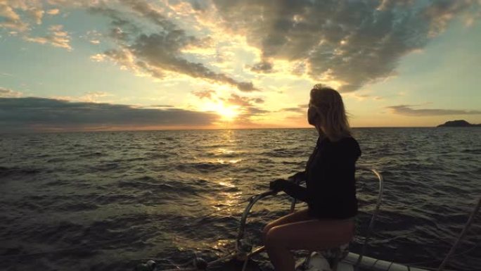 海中船尖上的一位女士观看日落并放松身心。