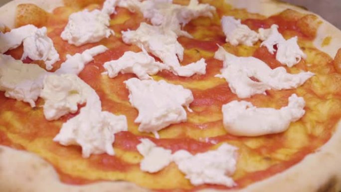 靠近披萨厨师的手，用高品质的意大利美食配料填充披萨。
