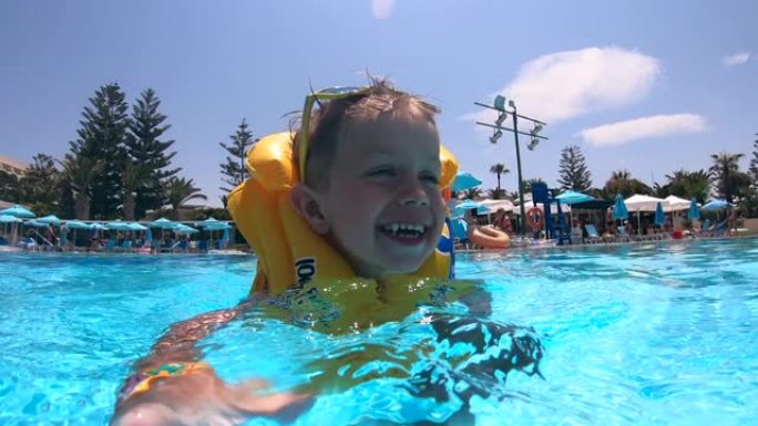 一个穿着救生衣的孩子在游泳池里快乐地游泳