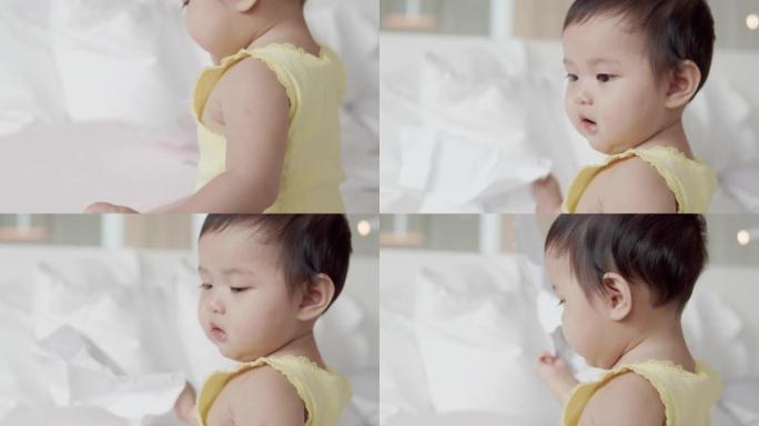 亚洲8个月女婴喜欢在家在白色床上玩耍。